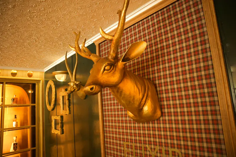 Venado dorado sobre pared de tartán