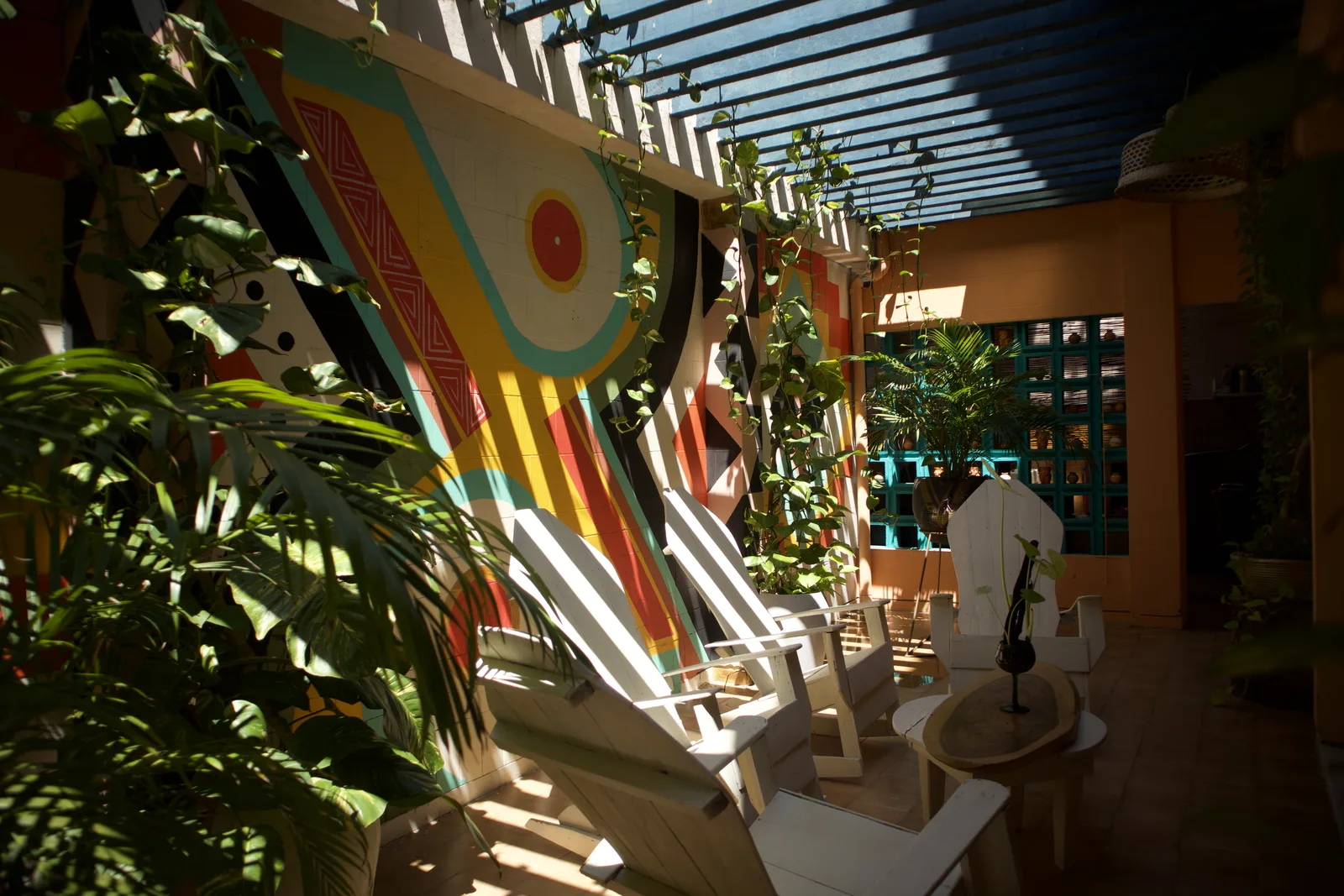Patio con mural geométrico de colores y luz entrando por las persianas